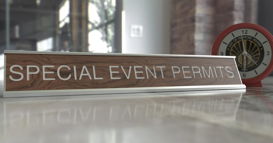 A photo of a countertop with a clock and name plate. The nameplate reads "SPECIAL EVENT PERMITS".