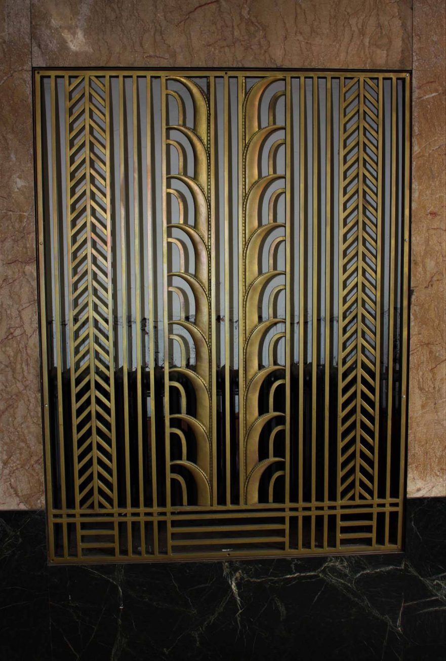 Heating grate cover in west vestibule of first floor lobby entrance, note that it pulls the main shape from the transom work.