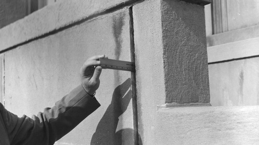 Man taking measurement of missing mortar prior to 1965 renovation.