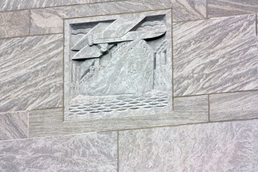 Carving on the upper area of the north and south extensions of City Hall, this is an Art Deco representation of a boat and plane, circa 2022.